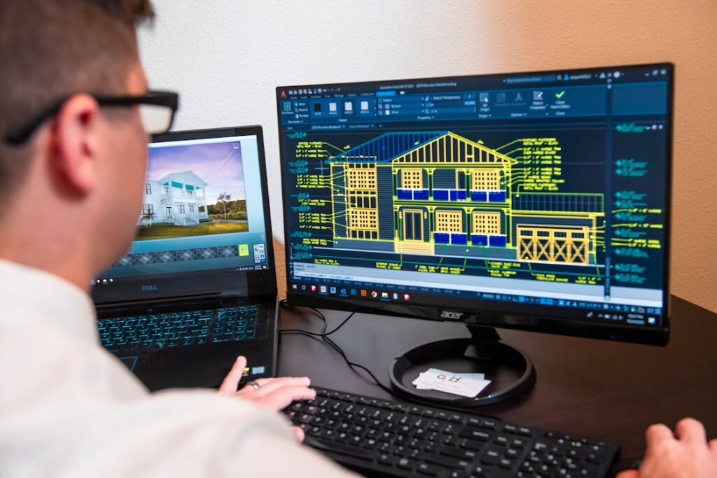 Architect reviewing detailed 3D building models on dual monitors in a modern office, illustrating equipment financing success for an architectural consulting firm